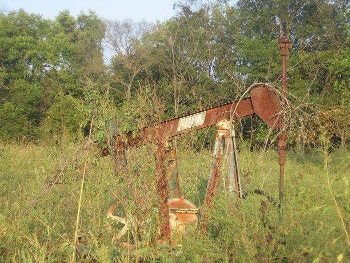 Old, rusty, abandoned oil pump at an abandoned well.