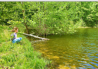 Young girl fishing off a stream bank