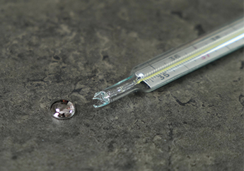 A broken mercury thermometer with liquid mercury spilling out