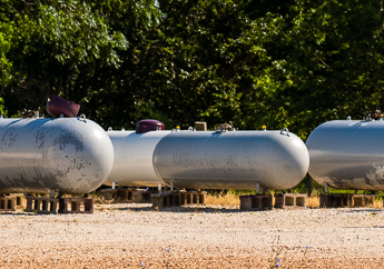 Several propane tanks sitting outside in a gravel lot