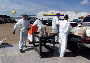 Hazardous waste contractors unloading and segregating pesticides at a collection event.