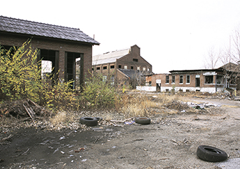 Brownfields property with several dilapidated buildings and weed-covered open spaces 
