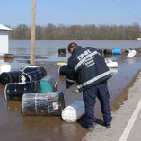 A department employee collecting abandoned drums during a flooding event