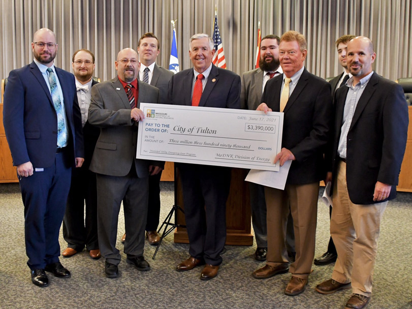 Governor Mike Parson hands a Municipal Utility Emergency Loan Program big check for $3.39 million to members of the City of Fulton.