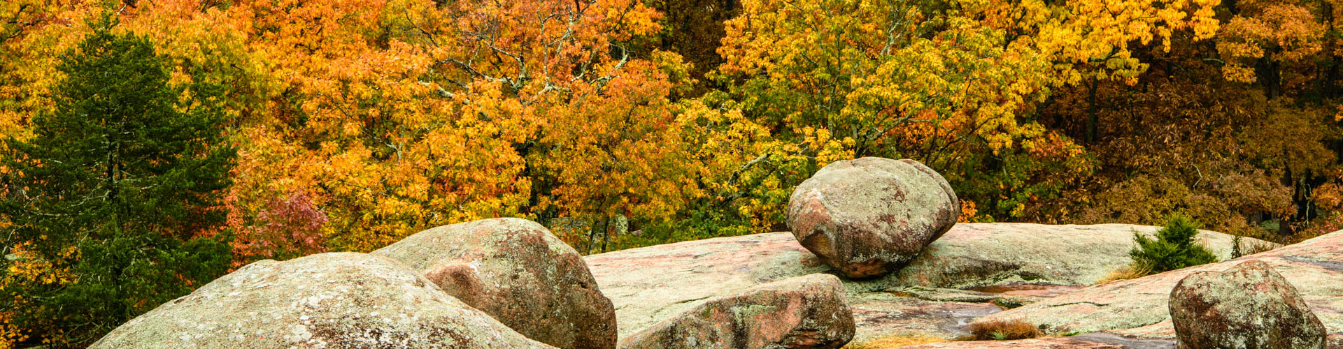 The elephant-shaped boulders at Elephant Rocks State Park are accented by the various shades of orange and red leaves on the trees in the background