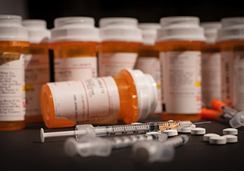 Prescription opioid pills and a syringe for illegal opioids