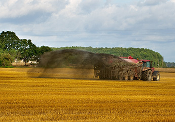 Red tractor in a field spreading liquid fertilizer