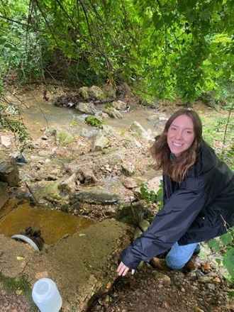 Intern Brook Anich observing a wastewater outfall in a wooded area