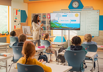 Primary school children sitting at their desks in a classroom listening to a presentation about the water cycle