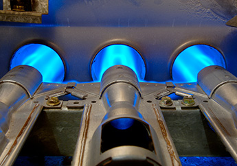 Blue flames blowing into round chambers withing a natural gas furnace.