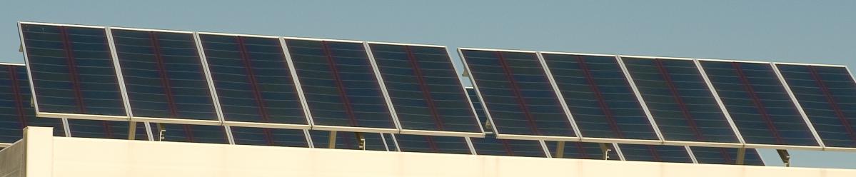 Several rows of solar panels located on a business building rooftop