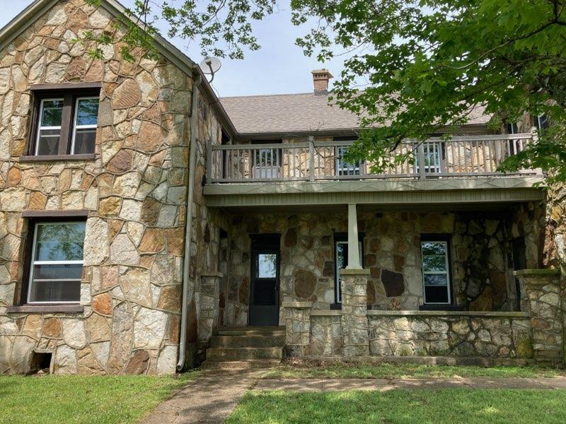 Old two-story rock house with balcony on second story.