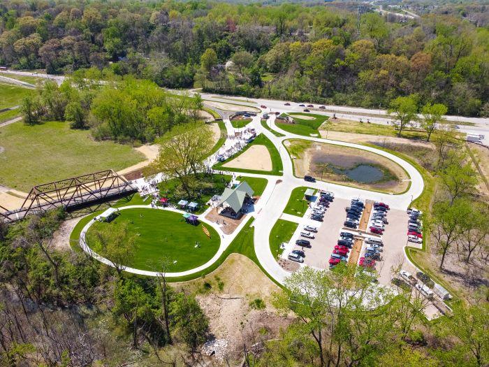 Aerial photo showing a bridge, green spaces, parking lot, building and road with trees in the background