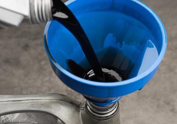 Used motor oil being poured into an empty oil container for disposal