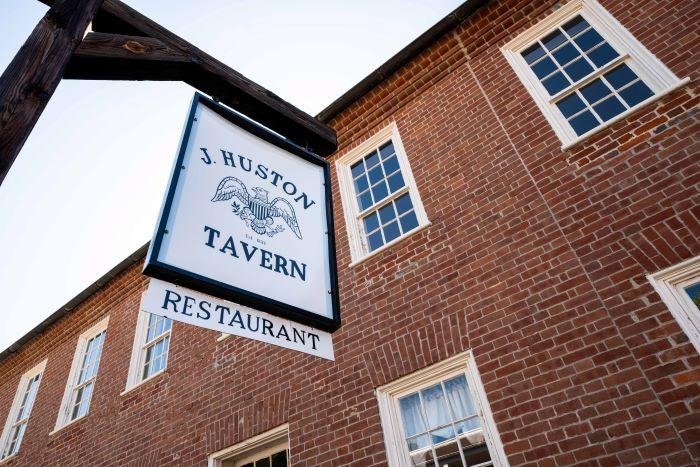 Brick building with sign that says “J. Huston Tavern Restaurant”.