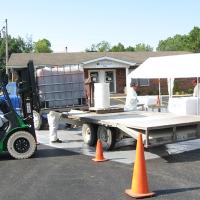 A hazardous waste contractor moving large containers of pesticides with a forklift.