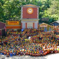 Teams of students pose for a photo at Silver Dollar City's outdoor stage, with old western store fronts as the backdrop.. 