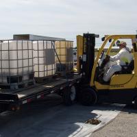 A hazardous waste contractor unloading bulk containers of pesticide from a participants trailer