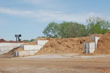 Piles of finished mulch separated by large concrete block dividers.