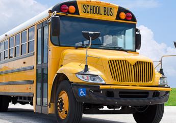 The outside of a generic yellow school bus, including the front view, bus door and half the right side