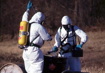 Department staff in level A hazardous materials suits with SCBA respirators sampling a 55-gallon metal drum