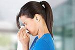 Woman blowing nose into tissue.