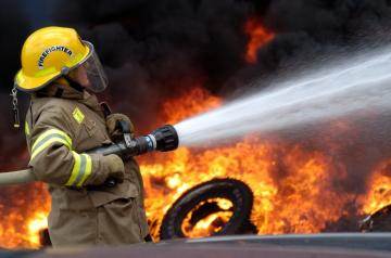A firefighter spraying a tire fire