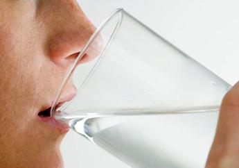 Person drinking from a clear glass of water