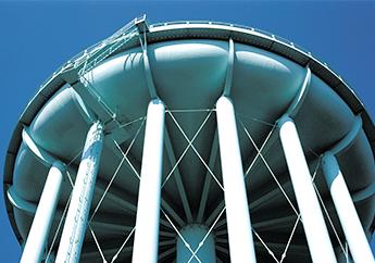 Closeup image of a public drinking water tower from below looking up at the main storage tank.