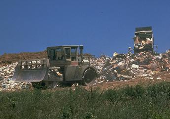 Heavy machinery moving solid waste on the active face of a landfill