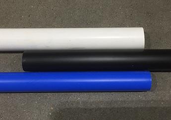 A white PVC pipe, black HDPE pipe and blue PEX pipe stacked on each other