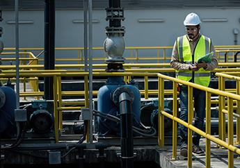 An engineer with a clipboard taking observing operations at a wastewater treatment plant