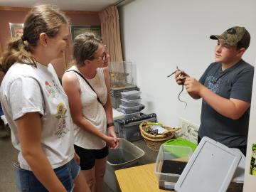 Team member from Prairie State Parks shows off two small snakes to visitors at the park