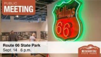 On left, man and woman view history exhibit at Route 66 State Park. On right hangs a green and red neon sign advertising Phillips 66.