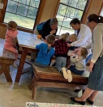 A group of children works on their craft project during Toddler Tuesday while parks teams members assist.