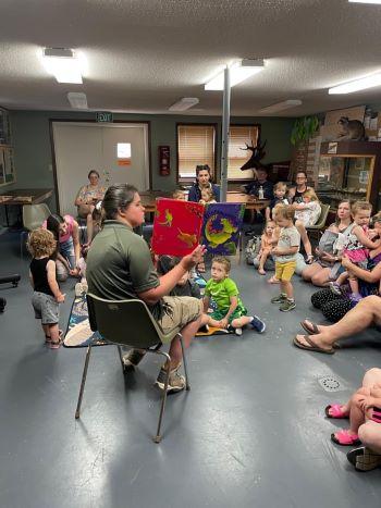 Woman reading a story to a group of toddlers and their parents. 