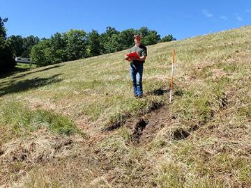 An intern observing a damaged area on the downstream slope of a dam for seepage