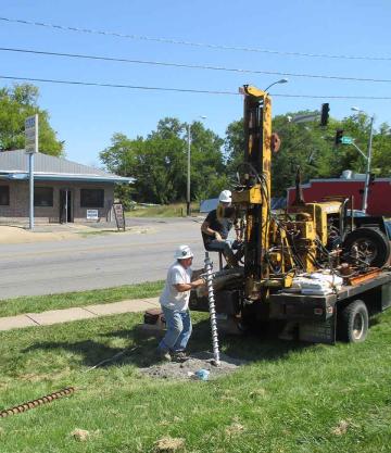 Two contractors using an auger drill rig to bore a hole