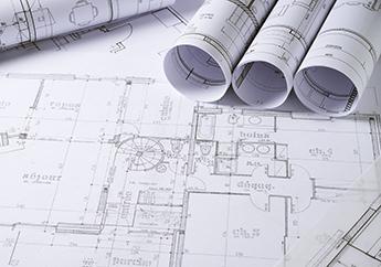 Four rolled up engineering plans laying across an unrolled engineering plan