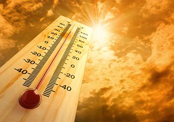 a thermometer displaying high temperatures underneath a bright yellow sun 