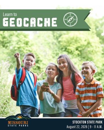 Four children in the outdoors using a mobile phone for geocaching.