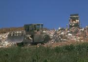 Heavy machinery moving solid waste on the active face of a landfill
