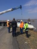 Environmental emergency response staff oversee flood container removal from highway.
